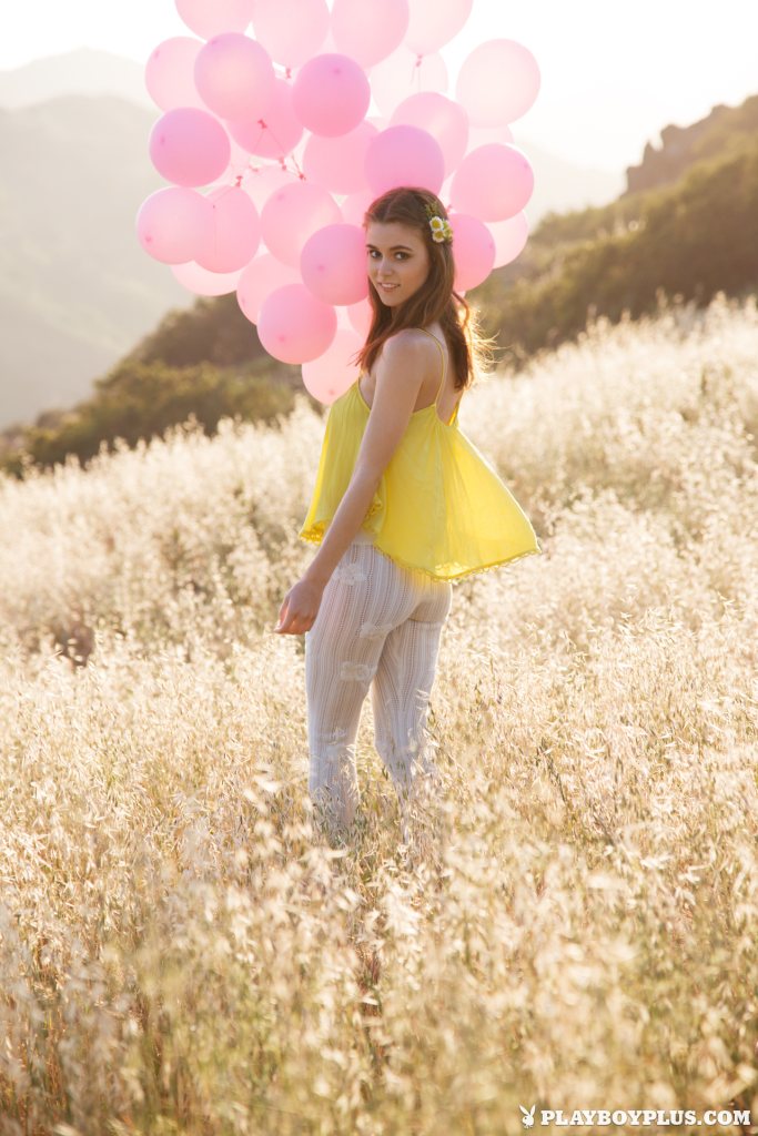 Amberleigh West is running naked in a meadow with a bunch of balloons